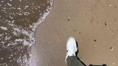 海辺の波打ち際を歩く男性の足