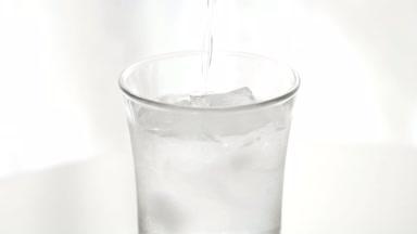 氷の入ったグラスに水を注ぐ