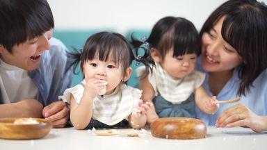 ご飯を食べる双子を見守る両親