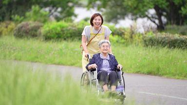 elderly woman taking a walk in a wheelchair while talking