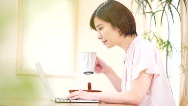 パソコン検索をしながらコーヒーを飲む若い女性