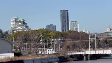 大阪城を背景に走る323系電車