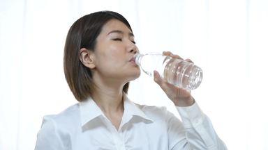 ペットボトルから水を飲む女性