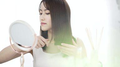 A woman looking in the mirror and straightening her hair with a comb