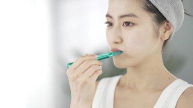 Profile of a woman brushing her teeth (left angle)