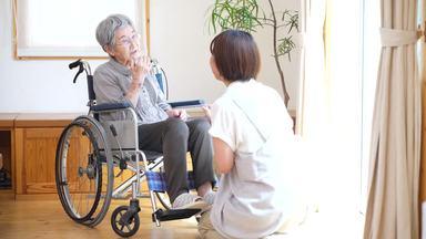 a woman listening to an elderly woman in a wheelchair