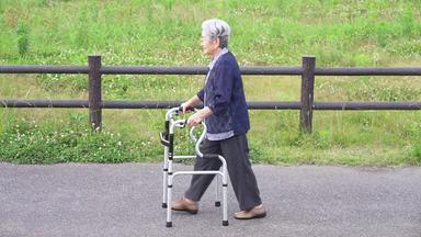 歩行器で歩く横向きの高齢女性