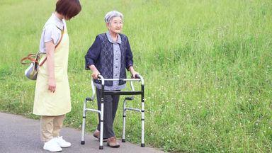 歩行器でゆっくりと歩く高齢女性