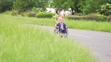 ゆっくりと車椅子で散歩する高齢女性