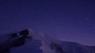 雪に覆われた爺ヶ岳と星空のタイムラプス