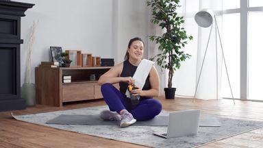 a chubby woman taking a break while looking at her laptop between exercises