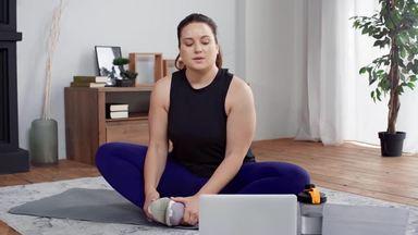 a chubby woman stretching while looking at her laptop