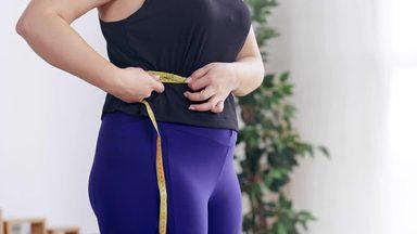 a woman measuring her waist with a major