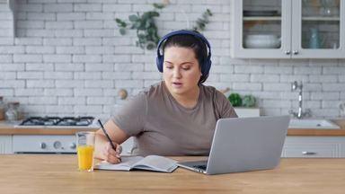 chubby woman using a laptop while taking notes