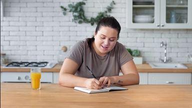 chubby woman writing notes while thinking