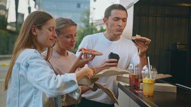 3 men and women eating pizza