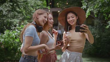 three women taking selfies outdoors
