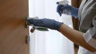 hotel housekeeper wiping the doorknob at the hands of a woman