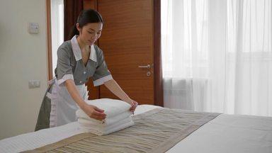 清潔なタオルをベッドに置くハウスキーパーの女性
