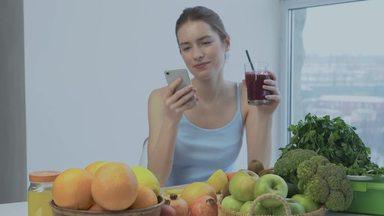 a woman looking at a smartphone while drinking juice