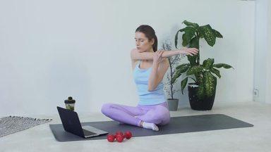 a woman stretching while looking at a computer