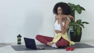 a woman stretching while looking at a computer