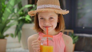 girl looking at the camera drinking orange juice