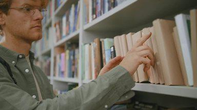 図書館で本を探す男性