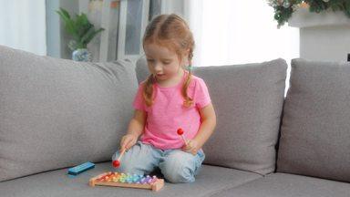 Girl playing with a xylophone on the sofa