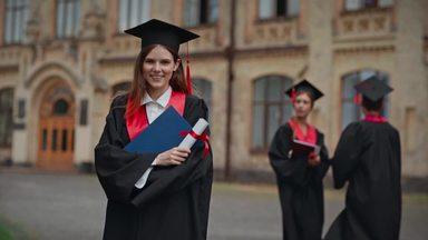 a woman holding a diploma and waving with a smile