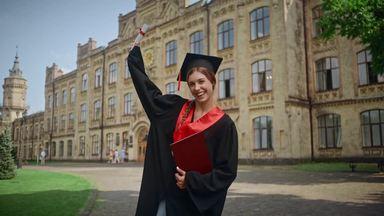 a woman jumping with a diploma
