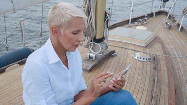 elderly woman using a smartphone on a yacht